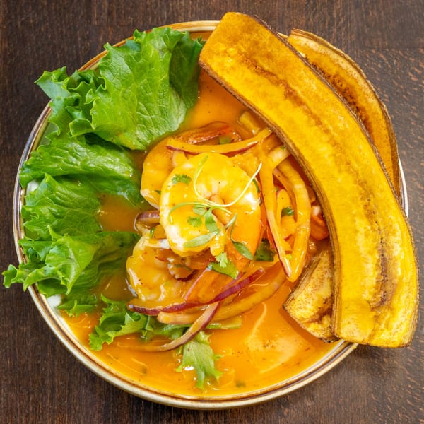 Peruvian ceviche with shrimp, red onion, lettuce, and plantain chips in a vibrant orange sauce.