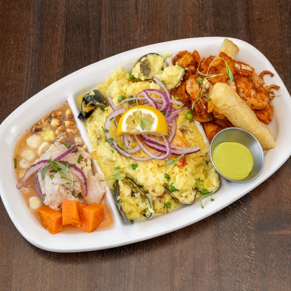A Peruvian seafood platter with ceviche, arroz con mariscos, fried calamari, and yuca fries.